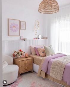 a bed room with a neatly made bed next to a chair and a lamp hanging from the ceiling