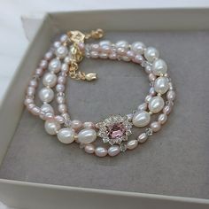 Material: Pink freshwater pearls, white freshwater pearls, cubic zirconia embellished oval settings with Swarovski antique pink crystals, small Swarovski crystal beads.  Size: The center pink stone is 6mm*8mm. The centerpiece is 1.1 cm*1.5 cm.  A. 16cm B. 17cm C. 18cm D. 19cm E. 20cm Please choose a size when you place the order. If you are not sure which size to choose, please leave a note to tell us your wrist size(without space). We will make the bracelet fit you.  Metal Color: Gold. Elegant Oval Beaded Jewelry, Elegant Pink Pearl Bracelet, Elegant Bracelet With Cubic Zirconia Round Beads, Elegant Cubic Zirconia Round Bead Bracelets, Oval Pearl Jewelry For Wedding, Oval Pearl Wedding Jewelry, Pink Pearl Drop Bracelet For Wedding, 1920s Luxury, Alley Rose