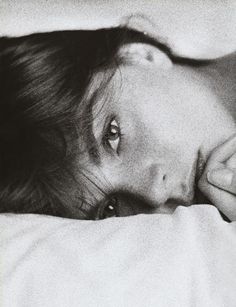 a black and white photo of a woman laying in bed with her head on the pillow