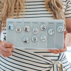 a woman is holding a set of buttons with words on them in front of her