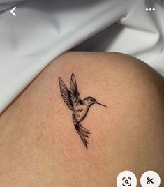 a small hummingbird tattoo on the back of a woman's left thigh,