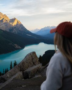 a woman standing on top of a mountain next to a lake