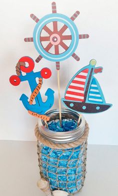 a jar filled with blue candy next to a wooden ship and sailboat topper