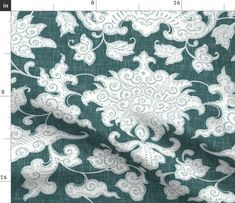 a green and white fabric with an ornate design on it's side, next to a ruler