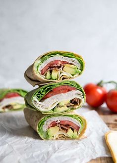 three wraps stacked on top of each other with tomatoes in the background and cheese slices