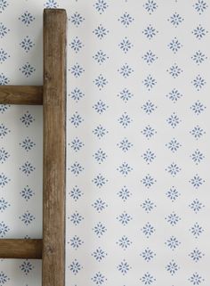 an old wooden ladder against a wall with blue and white flowers on the wallpaper