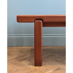 a wooden bench sitting on top of a hard wood floor next to a blue wall