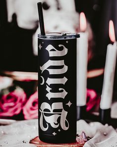 a black and white can with the word drink on it sitting next to some candles