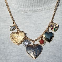 An eclectic mix of heart-shaped charms that tell a stories of love past present and future.  The Amour Collective Necklace brings together a mix of vintage-inspired heart lockets with textures with modern pops of color, creating timeless style. A unique memory, all coming together with perfect energy. Length: 16"-18"  Center Filigree Locket: 28mm  Left to Right Silver Opal Filigree Heart: 16mm Aura Radiant Heart Medallion Molten CZ Heart: 9mm Right to Left Red Cabachon Heart: 16mm High Polish Heart Locket: 22mm Gemstone Heart: 14mm 18mm x 13mm Mermaid Pearl Charm 16mm Pave Sun Charm 12mm Heart Charm 14K Gold Filled CZ Pave Stones Mermaid Pearl, Filigree Heart, Sun Charm, Locket Charms, Heart Gemstone, Pearl Charms, Heart Locket, Jewelry Inspo, Timeless Style