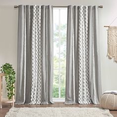 a living room with a white rug and gray curtains in front of a window that is open