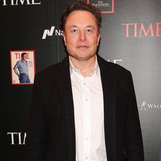 a man standing in front of a red carpet with a time magazine cover on it