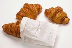 three croissants wrapped in paper sitting on top of a white countertop