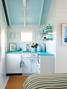 a small kitchen with blue counter tops and white walls, along with open shelving