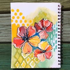 an art journal with watercolor flowers on the cover, sitting on a wooden surface