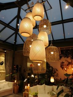 a living room filled with lots of white furniture and hanging lights over it's windows