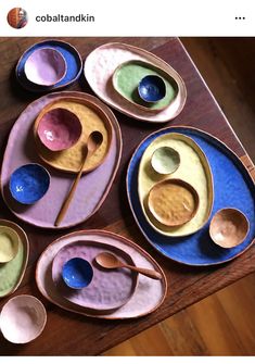 colorful bowls and spoons are arranged on a wooden table