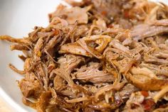 shredded meat in a white bowl on a wooden table