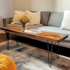 a living room with a couch, coffee table and pillows on the floor in front of it