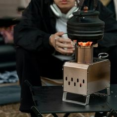 a man sitting on a chair next to a coffee pot with an open flame coming out of it