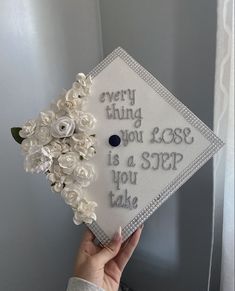 someone is holding up a graduation cap with flowers on it