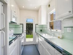 a kitchen with white cabinets and green counter tops next to a door leading to a yard