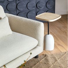 a white couch sitting next to a wooden table on top of a hard wood floor