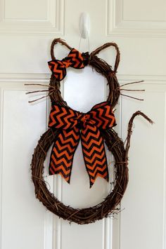 a wreath with an orange and black cat on it is hanging on the front door