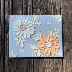 a blue and white tile with flowers on it sitting on a wooden table next to a piece of wood