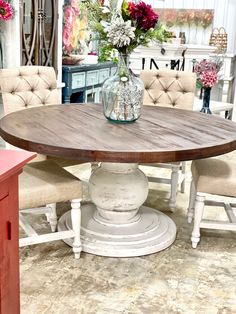 a dining room table with chairs around it and flowers in vases on the table