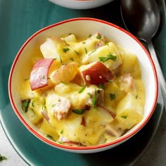 two bowls filled with food sitting on top of a green table next to spoons