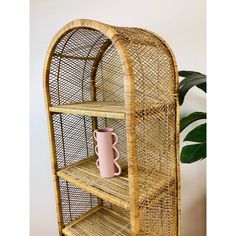 a wicker shelf with a pink vase on top