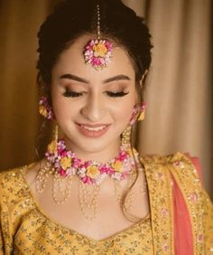 a woman in a yellow dress with pink and yellow flowers on her head, smiling at the camera