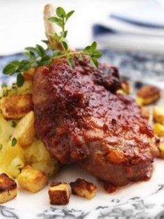 a piece of meat and potatoes on a blue and white plate with garnish