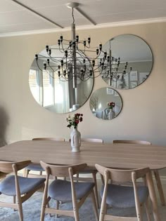 a dining room table and chairs with mirrors on the wall