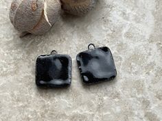 two black square shaped pendants sitting on top of a table next to some fruit