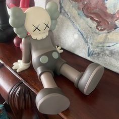 a gray and white toy laying on top of a wooden table next to a painting