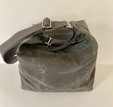 "This waxed canvas crossbody bag made of 10 oz fabric is water repellant, lightweight and beautiful! I've had this on my \"to do\" list for quite some time now. This bag is simple, sturdy and comfortable to wear and use. Fabric is doubled on the bottom and #5 nylon coil zipper with two pulls. Key hook inside. Choose from 4 colors and two hardware finishes. Charcoal is shown in the first few photos, then Olive, last photo is dark brown. Leather strap attachment may differ a little from photos. Pl Waxed Canvas Tote Bag, Waxed Canvas Backpack, Waxed Canvas Bag, Casual Tote Bag, Grey Bag, White Brass, Key Hook, Canvas Crossbody Bag, Brown Leather Strap