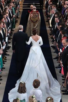 the bride and groom are walking down the aisle with their children in front of them