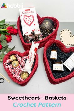 three heart shaped baskets filled with chocolates, candy and other items on a table