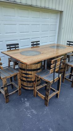 a wooden table and chairs made out of wine barrels are sitting outside in front of a garage door