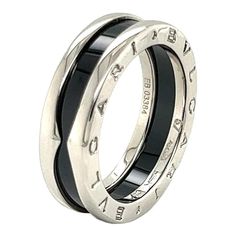 This is an authentic single band ring by Bvlgari from the B.Zero1 collection. It is crafted from sterling silver with a polished finish. This particular design honors Bvlgari’s ongoing philanthropic partnership with SAVE THE CHILDREN. The ring is in silver with black ceramic and is inspired by the B.zero1 jewelry collection and it is engraved with the charity’s logo. It is signed by the designer with the metal content and serial number.    Brand:  Bvlgari   Hallmark:  Bvlgari  Save The Children   Ag925 57 Made in Italy EB03384  Material: sterling silver and black ceramic      Measurements:  Band is: 7mm wide x 3mm high  Ring Size: 7.75  (57)    Weight:  6.8 grams S Logo, Black Ceramic, Band Ring, Sterling Silver Ring, Hallmark, Band Rings, Silver Ring, Sterling Silver Rings, Jewelry Collection