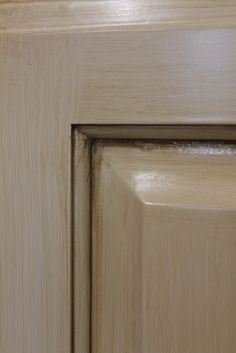 the corner of a wooden cabinet door that has been painted light brown with white trim