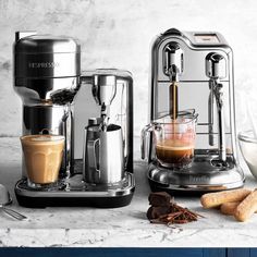 two espresso machines sitting next to each other on a counter