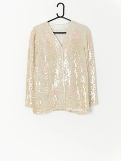 Vintage beaded sequin jacket in ivory and pink. This jacket features a hook and loop chest closure and a smooth lining. The jackets pattern features transparent sequins on a ivory material and an abstract beaded baby pink pattern. Made from a synthetic material. This jacket is the perfect party piece! Our recommended size: Small / Medium Label says: No size label Condition: Very good*: has a small part of thread with slight discolouration on the front right side, and what looks like a mark from Elegant White Sequined Outerwear, Spring White Embellished Outerwear, Summer Party Sequined Outerwear, Summer Party Outerwear With Sequins, White Sequined Long Sleeve Outerwear, White Sequined Outerwear For Party, Long Sleeve Sequin Outerwear For Wedding, Spring Party Embellished Outerwear, Festive Long Sleeve Sequin Outerwear