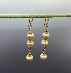 Unique presentation of peach freshwater pearls, antique gold spacers, and filigree bead caps in these elegant dangle earrings. The dangles are connected to each other and to the gold filled earwire through gold filled wrapped loops.  The earrings are about 1 1/4 inches long, measured from the earwire, and come nestled comfortably on a bed of cotton in a white cardboard box. Made in the USA by me. NA-821-0624-1111 Delicate Gold Pearl Chandelier Earrings, Gold Pearl Chandelier Earrings Delicate Style, Gold Pearl Chandelier Earrings In Delicate Style, Elegant Gold Dangle Beaded Earrings, Elegant Gold Beaded Dangle Earrings, Delicate Gold Chandelier Earrings With Pearl Drop, Gold Beaded Earrings With Pearl Drop For Gifts, Delicate Gold Earrings With Dangling Beads, Gold Pearl Drop Beaded Earrings For Gift