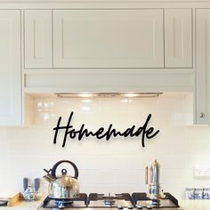 the words homemade are written in cursive black ink on a white kitchen backsplash