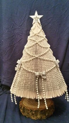 an origami christmas tree made out of folded book pages on a wooden stand