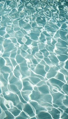 an empty swimming pool with water ripples and sun reflecting off the surface on it