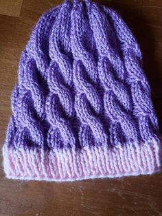 a purple knitted hat sitting on top of a wooden table next to a pair of scissors