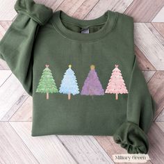 Get ready to celebrate the holidays with this lovely Christmas Tree Sweatshirt! Featuring five colorful Christmas Trees, this cozy shirt brings a cheerful touch to the festive season. Christmas tree sweatshirt, cute holiday shirt, festive christmas tree design, Christmas Tree gift, cozy Christmas sweater, funny Christmas shirt, winter-themed holiday apparel, winter shirt, holiday christmas tree sweatshirt, Christmas lights, Christmas fashion, Christmas crewneck, cute Christmas sweater, funny holiday apparel, cozy winter outfit, Christmas party shirt, unique Christmas gift for tree lovers. Product Details Our Unisex Gildan sweatshirts offer a comfortable and stylish fit that's perfect for everyday wear. These classic fit sweatshirts are true to size for a relaxed feel, and feature a tear-aw Vintage Christmas Shirt, Christmas Sweater Funny, Cute Christmas Sweater, Christmas Party Shirts, Cozy Winter Outfits, Cute Christmas Tree, Christmas Crewneck, Winter Shirts, Christmas Tree Design